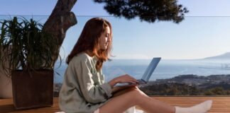 Digitale Nomaden: Den Traum von Freiheit und Unabhängigkeit leben Frau sitzt am Meer vor ihrem Laptop