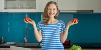 Abnehmen: Diese Online-Coaches machen es Ihnen leicht Frau mit Gemüse und Laptop in der Küche